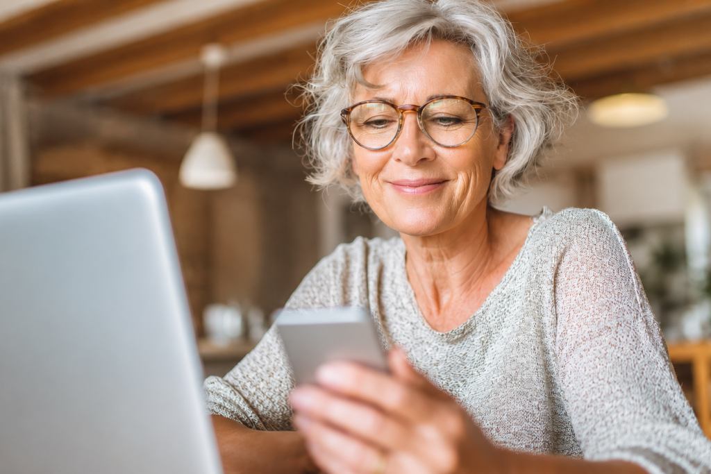 Mature woman focused on her phone and computer