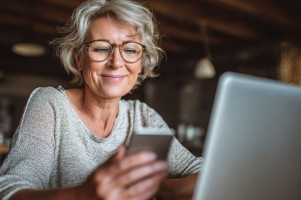 mature woman using her laptop and phone